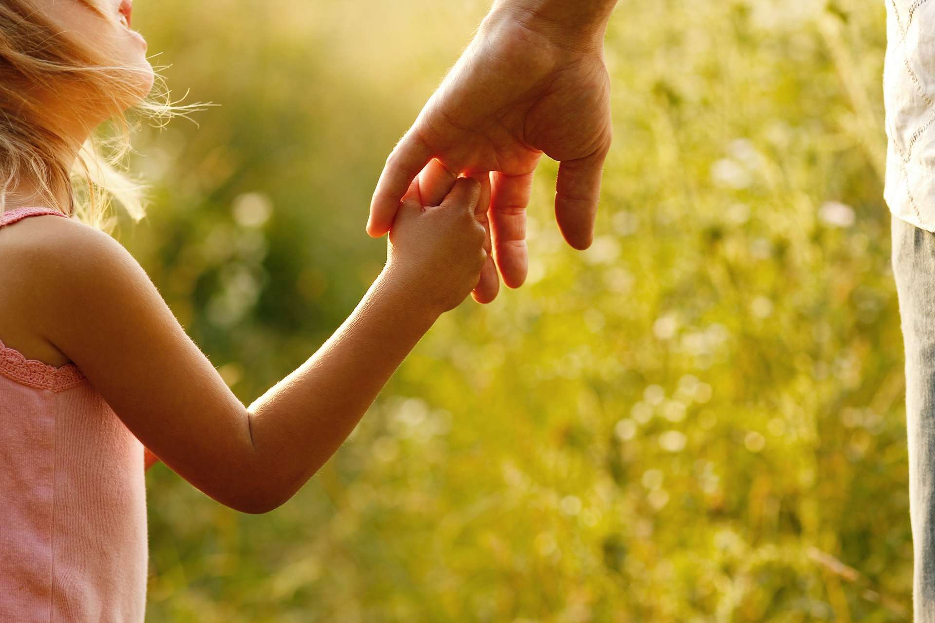 a parent holds the hand of a small child